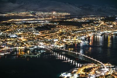 Aerial view of river amidst illuminated buildings in city at night