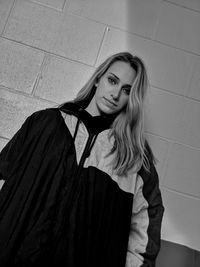 Portrait of young woman standing against wall