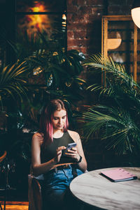 Woman reading good news on mobile phone during rest in coffee shop.