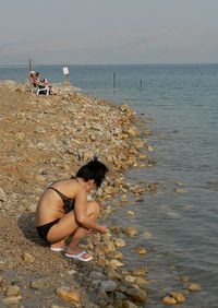 Woman crouching on sea shore at beach
