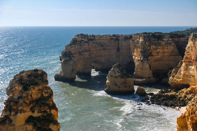 Rock formations by sea against sky