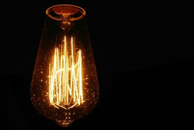 Close-up of illuminated light bulb against black background