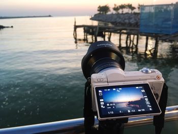 Close-up of camera on beach against sky