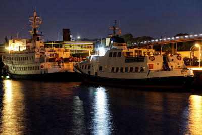 Illuminated ship in sea against sky in city at night