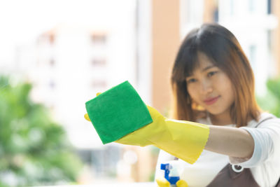 Smiling young woman cleaning glass window