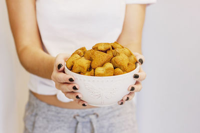 Midsection of woman holding cookies in bowl at home