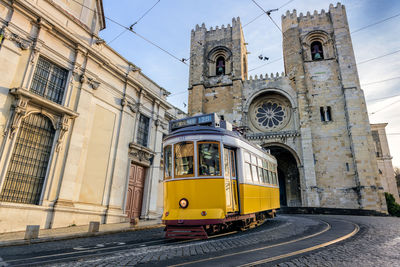 Yellow cable car on street by duomo santa maria del fiore against sky