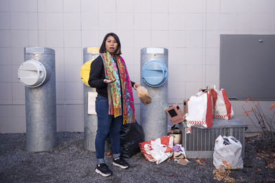 Portrait of young woman standing against wall