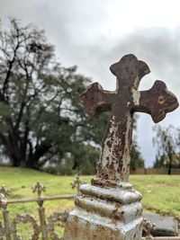 Close-up of cross in cemetery against sky