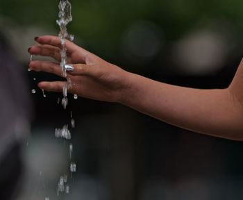 Close-up of hands holding water from faucet