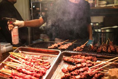 Midsection of chef preparing food on barbecue grill at commercial kitchen