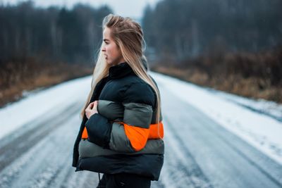 Side view of woman standing on snow covered road