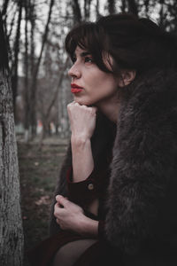 Portrait of woman looking away while sitting on tree