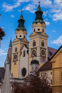 Low angle view of clock tower amidst buildings against sky