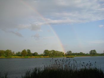Scenic view of rainbow over lake against sky