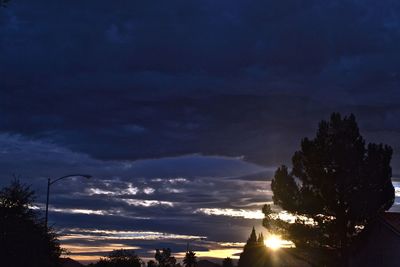 Low angle view of silhouette trees against dramatic sky
