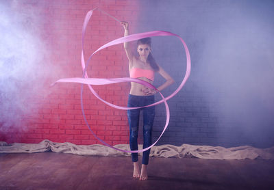 Portrait of woman standing against pink wall