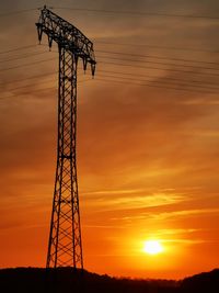 Low angle view of silhouette electricity pylon against sky during sunset