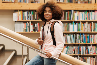 Portrait of young woman standing in library