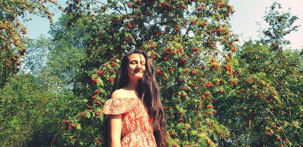 Portrait of young woman standing against trees