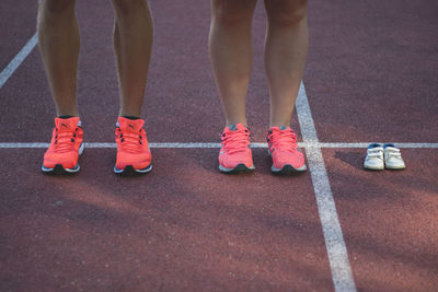 Low section of couple with baby shoes standing on sports track