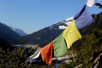 Close-up of multi colored flags hanging on mountain against sky