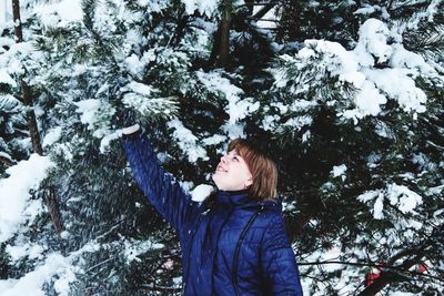 Girl standing by tree during winter