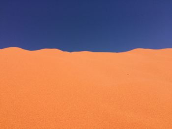 Low angle view of desert against clear blue sky