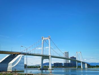 Suspension bridge over river against clear blue sky