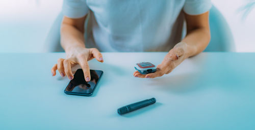 Midsection of woman using smart phone on table