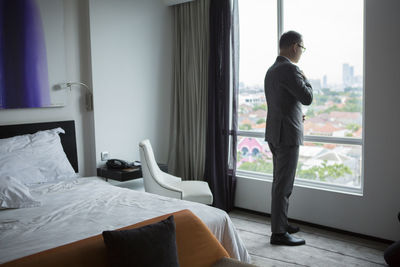 Rear view of man standing on bed at home