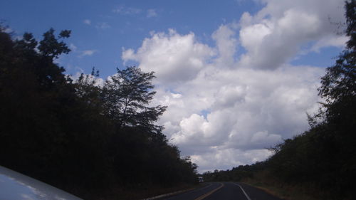 Road amidst trees against sky