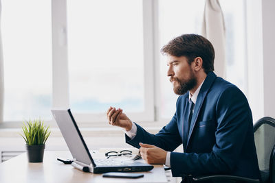 Young man using phone while sitting on table