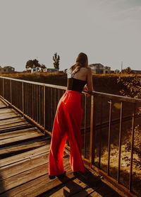 Full length of woman standing on footbridge against clear sky