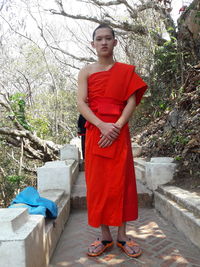 Full length of young woman standing against trees