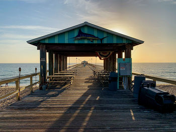 Pier over sea against sky during sunset