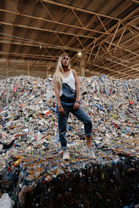 Portrait of young woman standing by garbage
