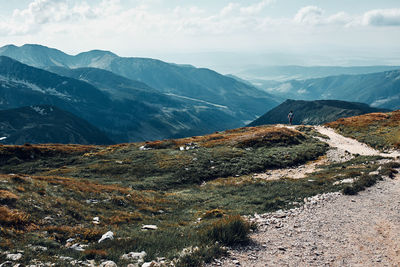 Young man with backpack hiking in a mountains, actively spending summer vacation