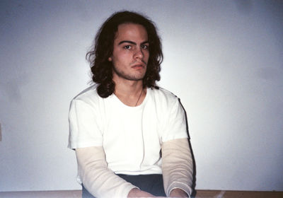 Portrait of young man sitting against wall at home