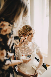 Midsection of woman with arms raised standing against wall