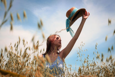 Woman with arms raised on field against sky