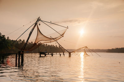 Fishing nets in lake against sky during sunset