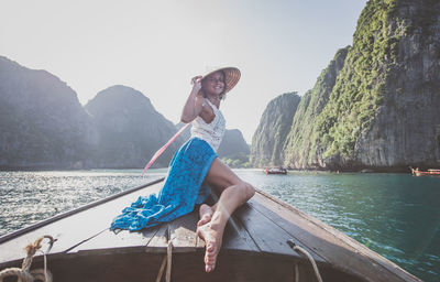 Woman sitting on boat against mountains against sky