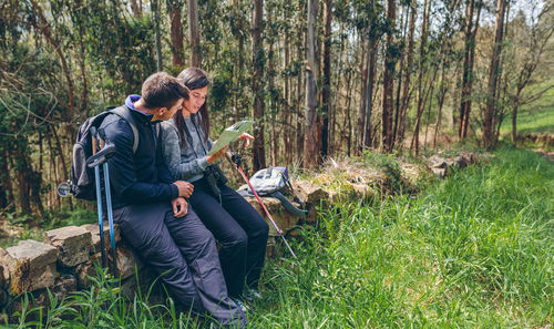 Young man sitting on land in forest