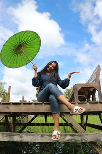 Woman sitting on bench against sky