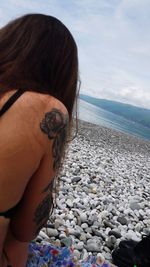 Rear view of woman on beach by sea against sky