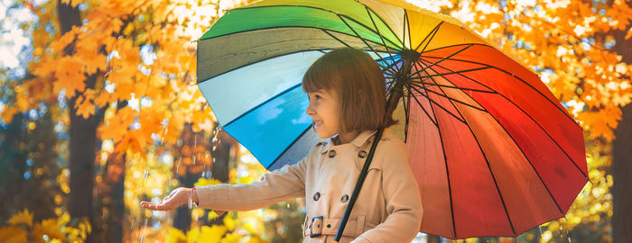 Cute girl holding umbrella at autumn forest