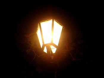 Close-up of illuminated silhouette light against sky during sunset