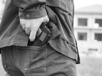 Midsection of thief removing gun from back pocket