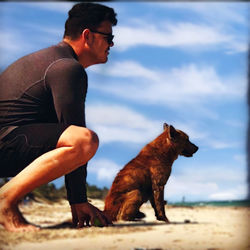 Side view of man with dog against sky